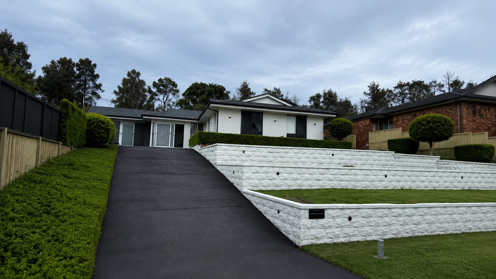 Premium white stone retaining wall with concrete driveway by Ted's Renovation Services