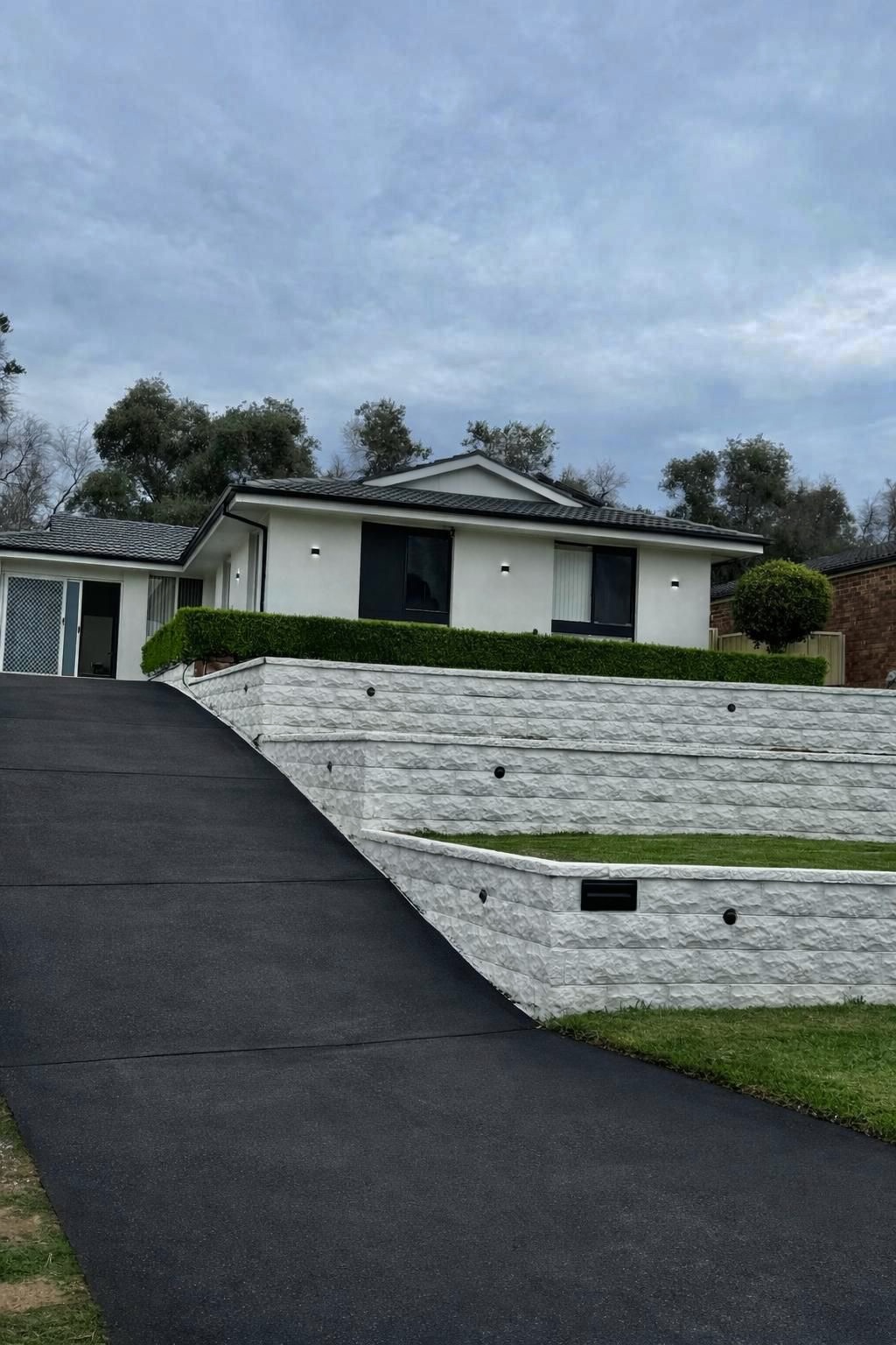Premium white stone retaining wall with concrete driveway by Ted's Renovation Services