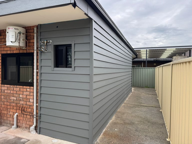 Modern utility room extension attached to brick house with fenced concrete pathway, South West Sydney