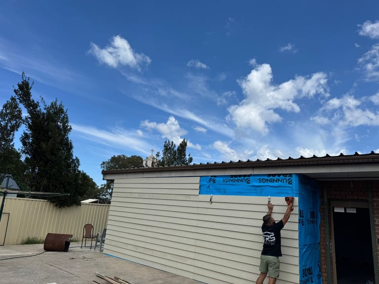 Person standing in front of corrugated metal building with blue door under clear blue sky