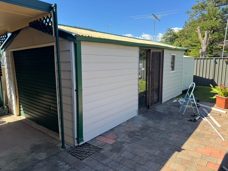Modern white and green shed with covered carport area, brick patio, Parramatta
